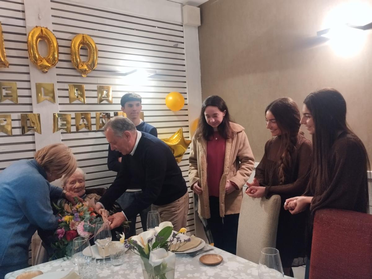 Isabel Iglesias y José Carlos Loredo colocan el ramo de flores en el regazo de Maruja Llaneza, con sus bisnietos Pablo, Alba, Blanca e Inés Loredo, a la derecha.