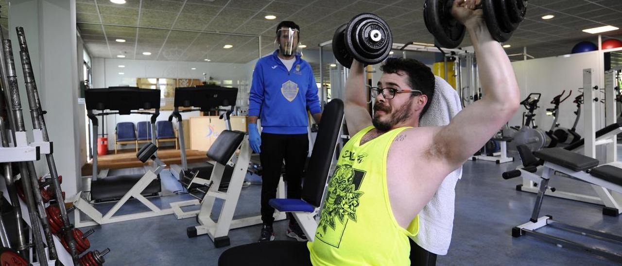 Un usuario se ejercita en el gimnasio de Cruces en presencia de un monitor. // Bernabé/Javier Lalín