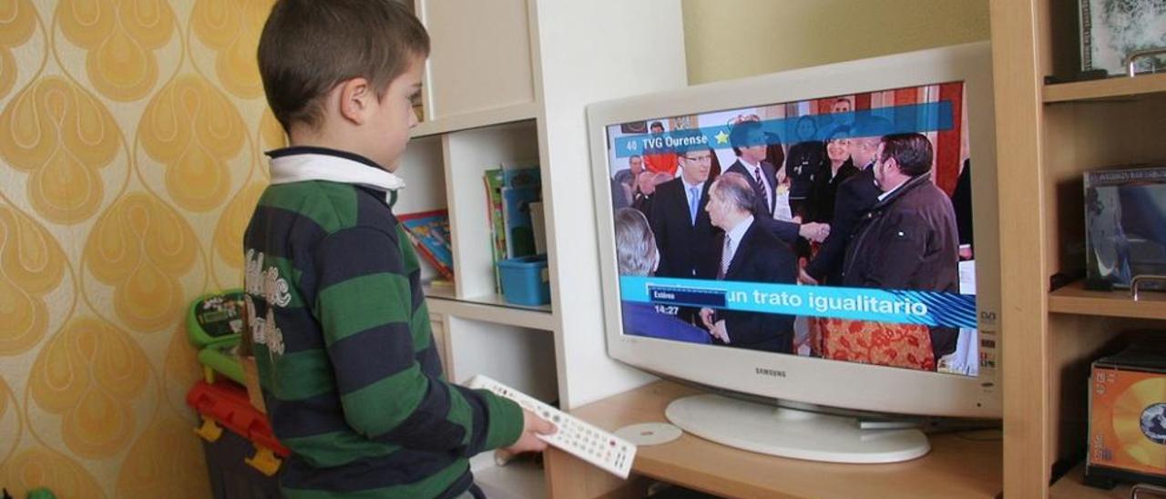 Un niño con el mando a distancia ante un televisor en un piso de Ourense. // I. Osorio