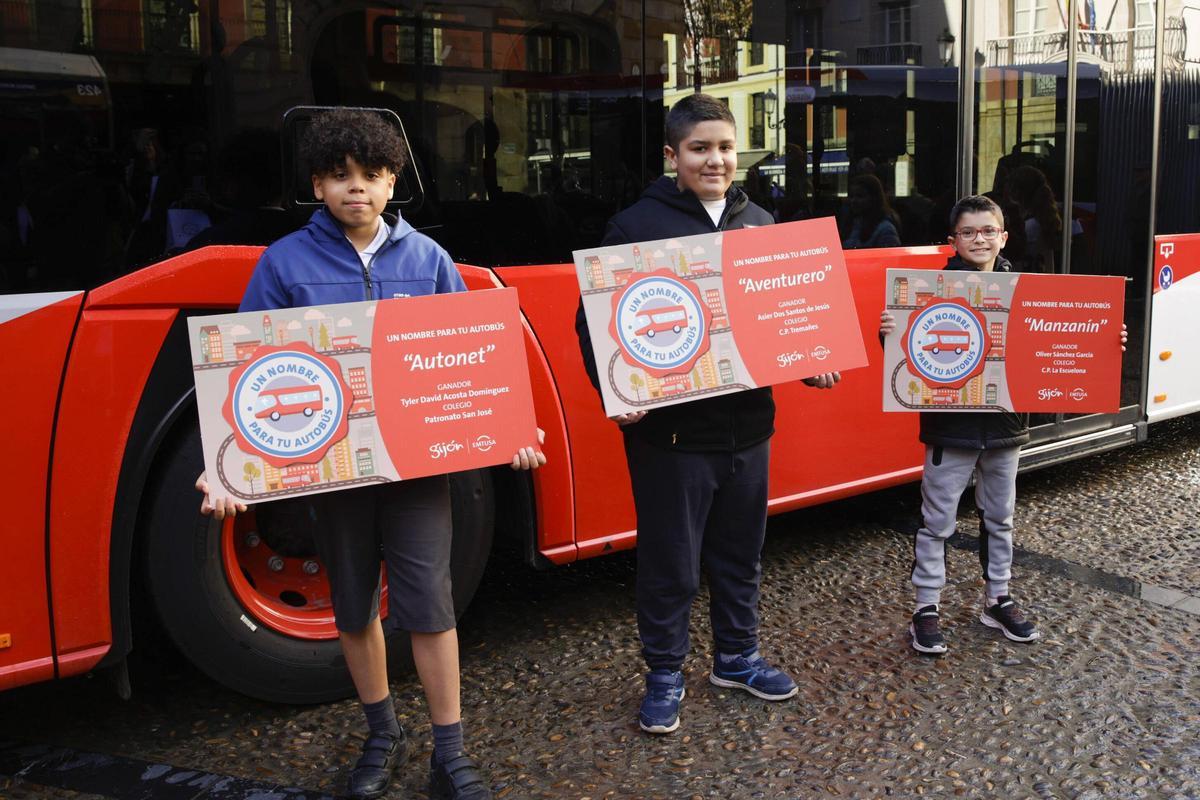 Los tres ganadores del concurso de Emtusa posan con el cartel con el nombre elegido para cada autobús.
