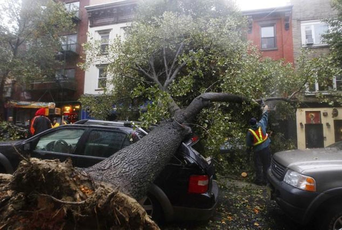 Un treballador talla un arbre en diverses parts després d’haver caigut sobre un cotxe a causa dels forts vents que van castigar la regió de Hoboken a New Jersey, després de l’arribada del ’Sandy’.