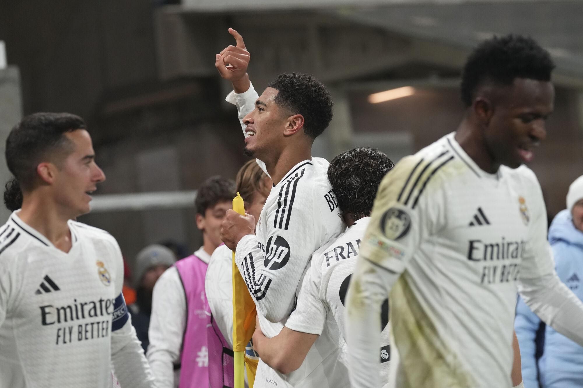 Real Madrid's Jude Bellingham, center, celebrates with his teammates after he scored his side's third goal during the Champions League opening phase soccer match between Atalanta and Real Madrid at the Bergamo's stadium, in Bergamo, Italy, Tuesday, Dec. 10, 2024. (AP Photo/Antonio Calanni). EDITORIAL USE ONLY / ONLY ITALY AND SPAIN