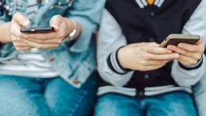 Dos adolescentes, mirando sus móviles.