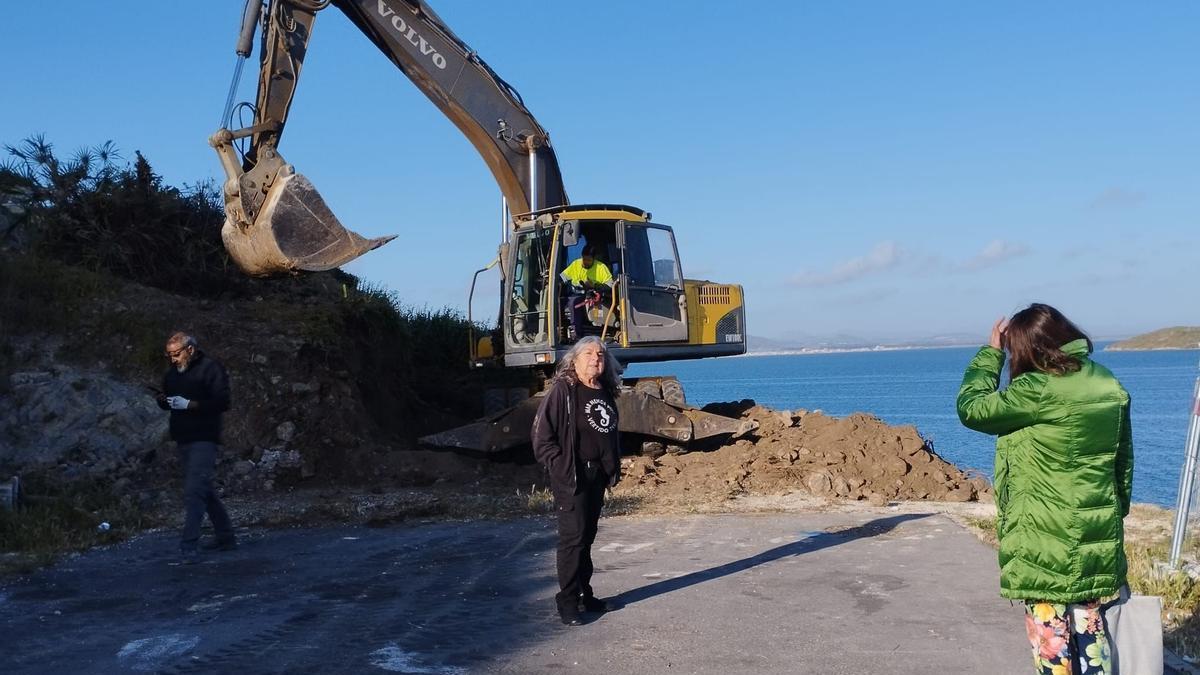 Varios vecinos, ayer, frente a la pala excavadora en la Cala del Pino.