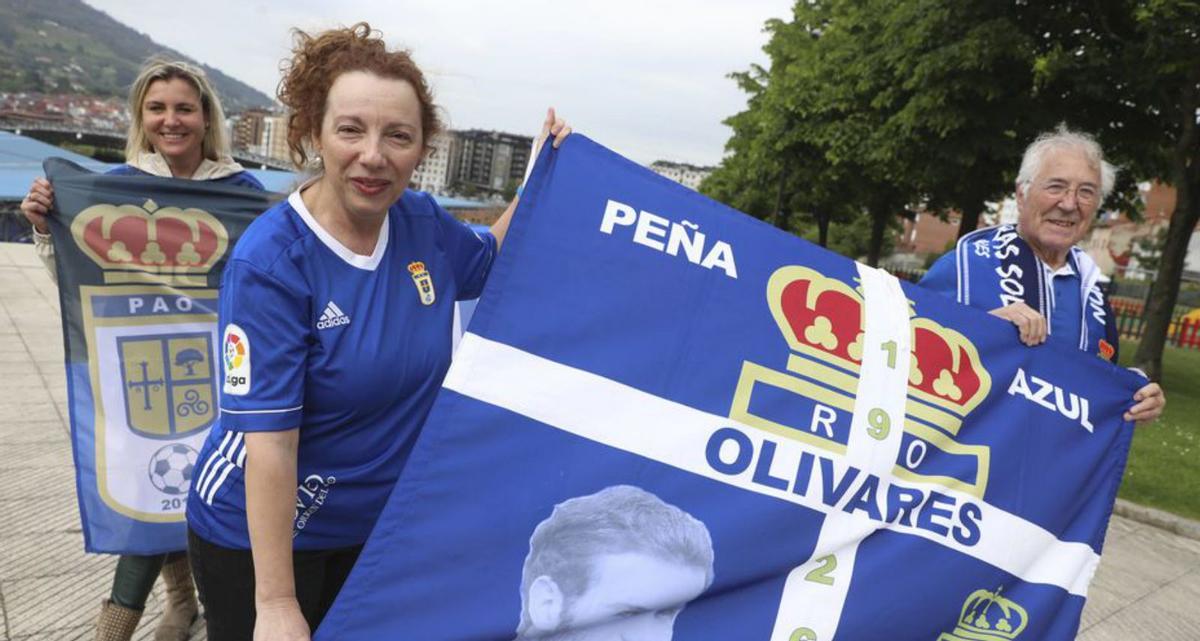 Lucía Castro, María Álvarez y Joaquín Salas posan con las banderas de la peña azul Olivares en el parque Juan Mata de Oviedo. | Luisma Murias
