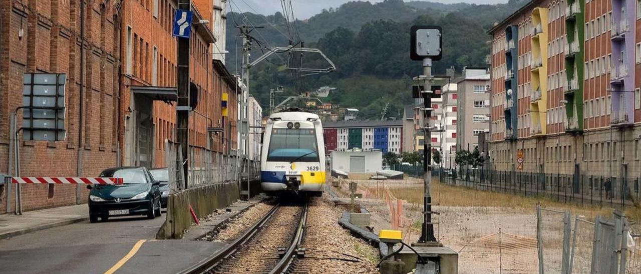 Un tren circula por La Felguera, junto a la zona bajo la que se construyó el falso túnel.