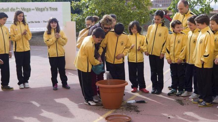 Alumnos riegan la encina recién plantada junto a una profesora de la Universidad de León, que ayer dio una charla.