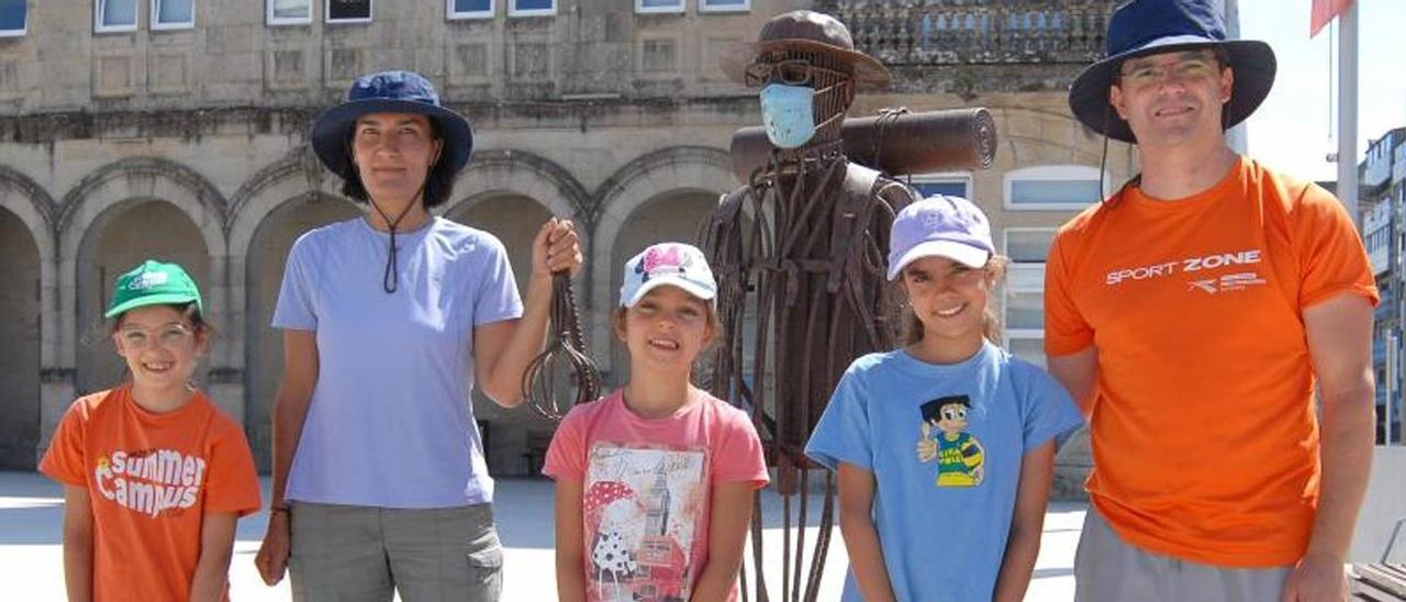 La familia Alves pisa ante la escultura del peregrino en la Praza da Constitución.  | BERNABÉ/ JAVIER LALÍN