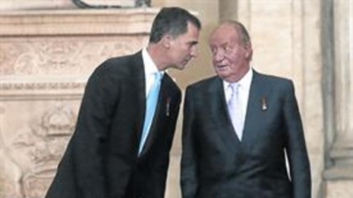 Juan Carlos dialoga con su hijo, ayer durante la firma de su abdicación.