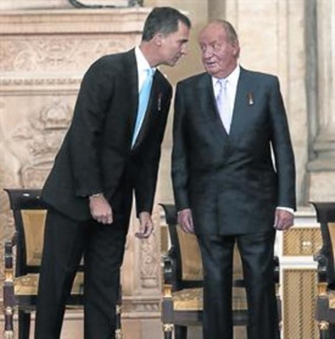 Juan Carlos dialoga con su hijo, ayer durante la firma de su abdicación.