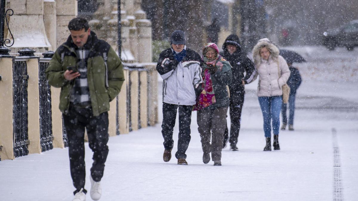 Varias personas pasean en Teruel bajo la nevada del pasado día 5 de enero.
