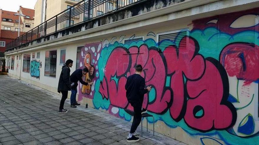 Casares acompaña a dos chavales en la elaboración de los grafitis.