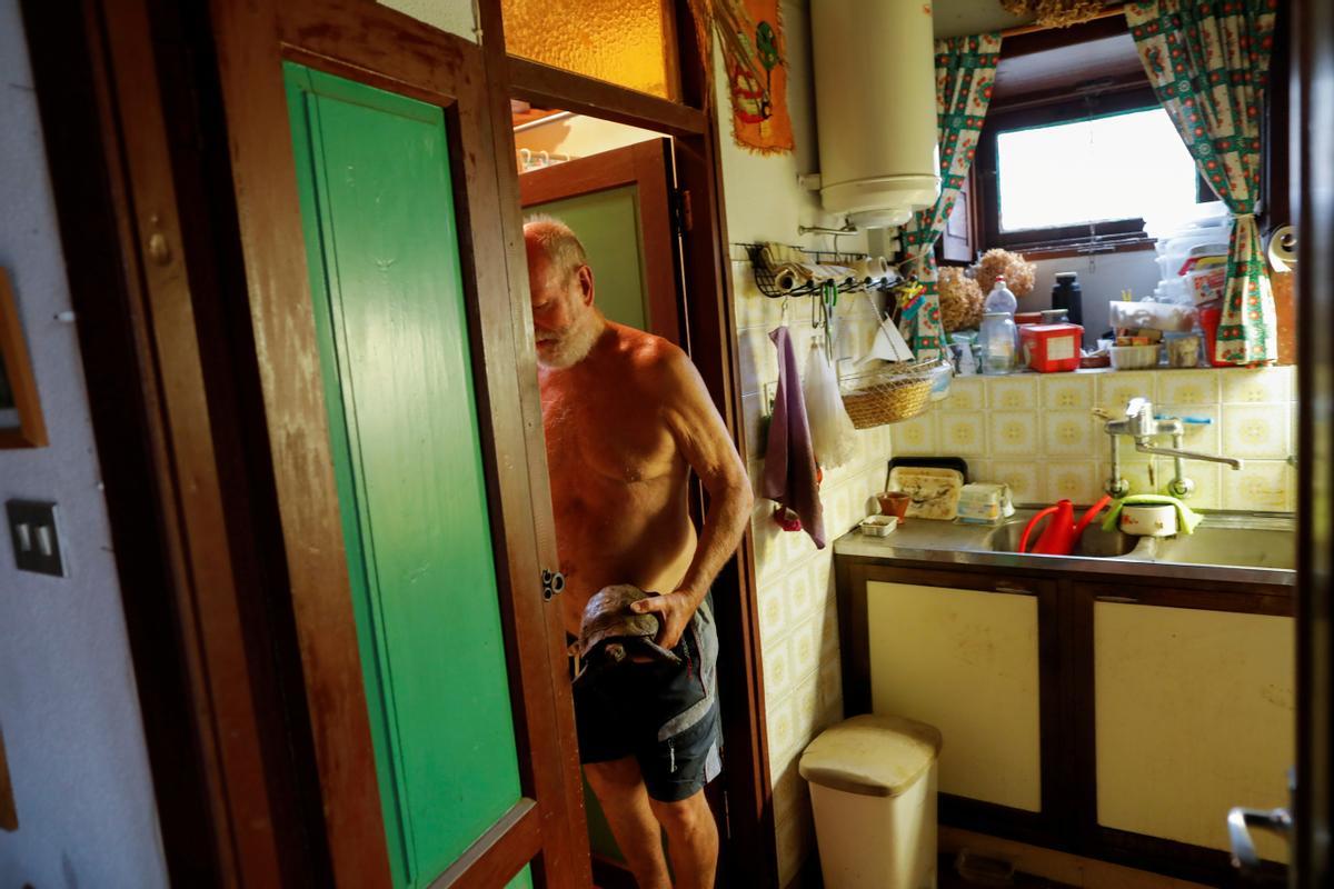Gert Waegerle, de 75 años, lleva una tortuga al interior de su casa, a la que ha podido volver tras ser evacuado por la amenaza del volcán de La Palma.