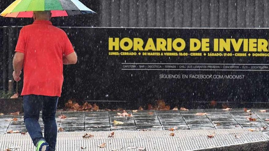 Un hombre se protege de la lluvia en una calle de A Coruña.