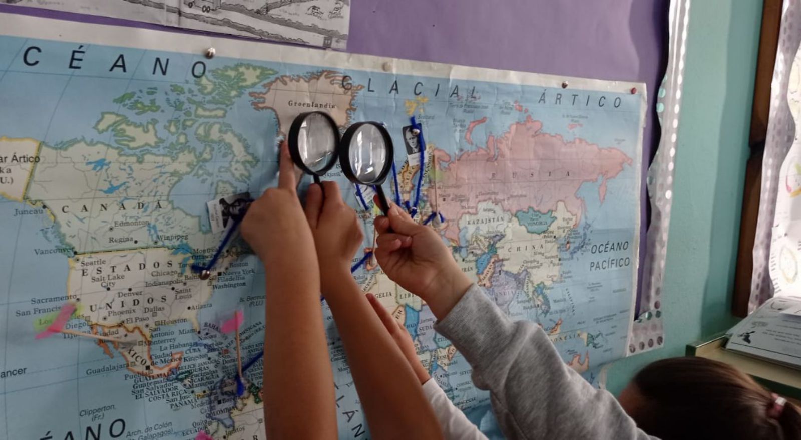 Dos escolinos averen con lentes al mapa de Groenlandia pa estudiar la perda de xelu y la xubida del nivel del mar. 