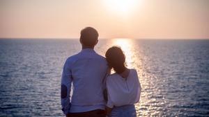 Una pareja contempla el mar de espaldas.