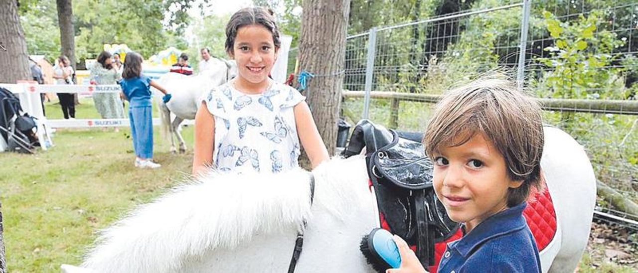 Salma Sofía y Pelayo Elías cepillan un poni. | Ángel González