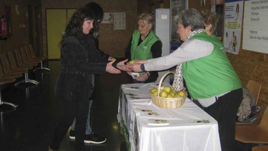 Voluntarias entregan a dos usuarias del centro de salud folletos informativos y manzanas. Foto