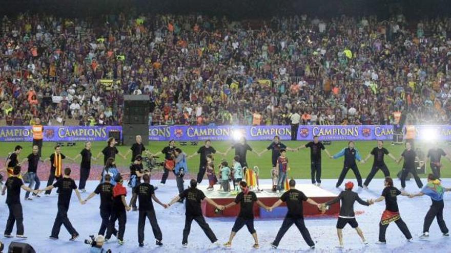 Los jugadores y técnicos del Barça rodean el trofeo formando un corro en el Camp Nou.