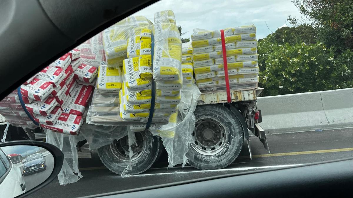 La carga de sacos de cemento que transportaba el camión ha quedado desplazada.