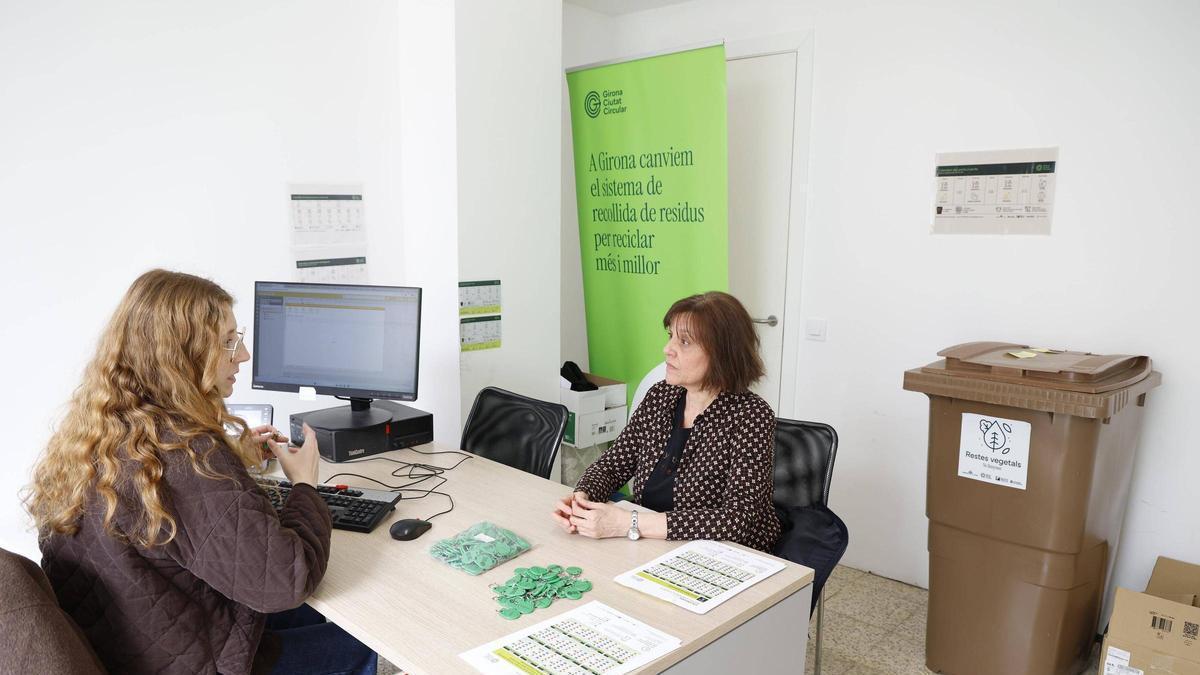 Una veïna recull el clauer de residus en una oficina de suport de Girona.