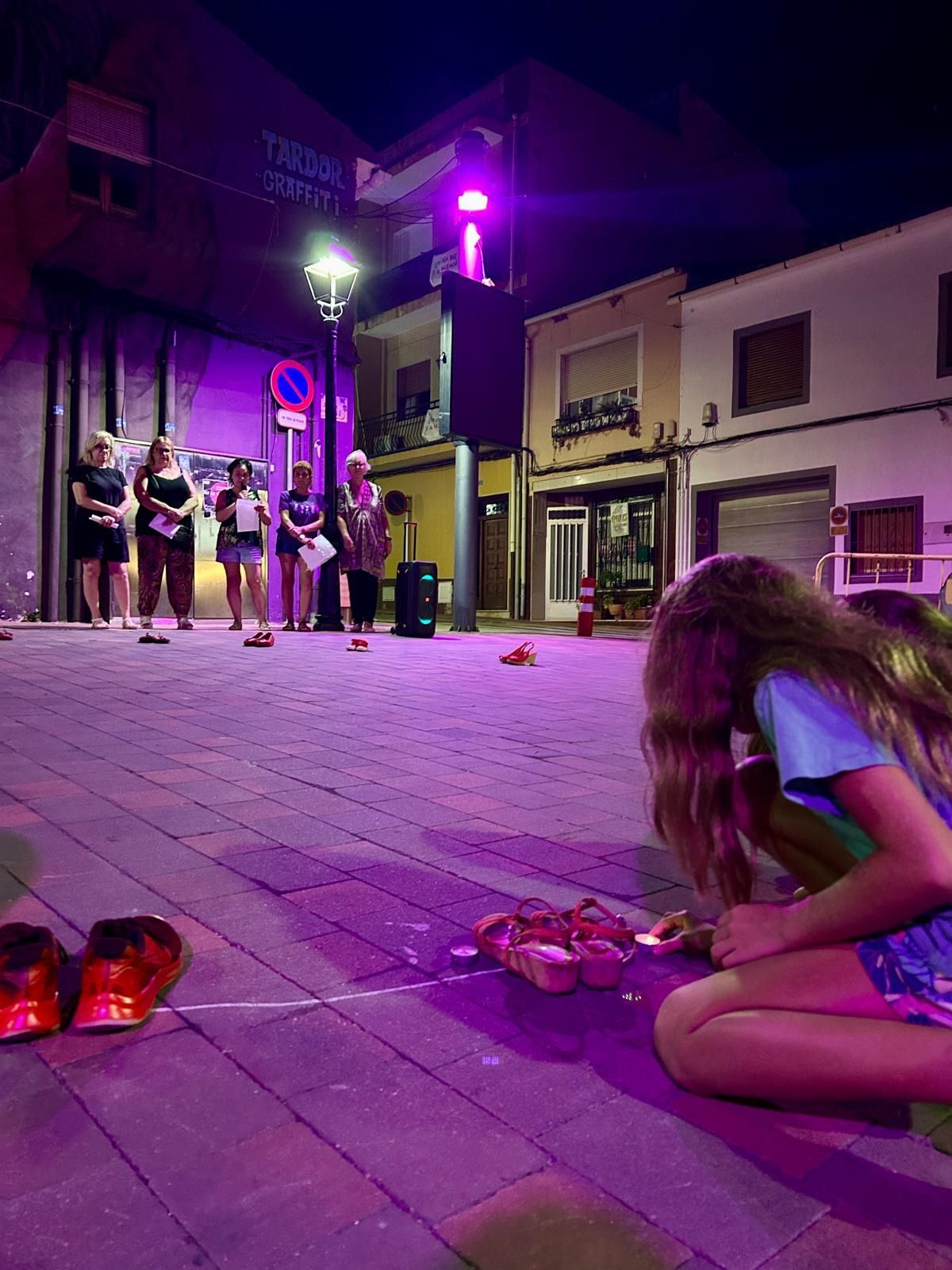 Dos niñas encienden un cirio junto a un par de zapatos rojos