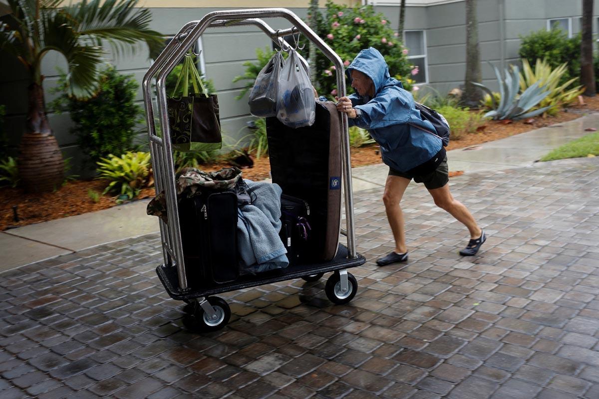 Una turista empuja un carrito bajo la lluvia a la llegada a un hotel,  en Fort Myers, Florida.