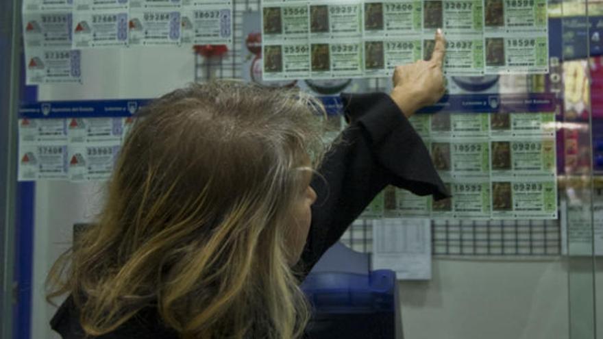 Una mujer compra un décimo de Lotería de Navidad.