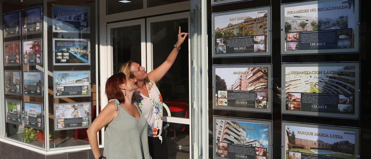 Clientes miran los anuncios de una inmobiliaria en Málaga.