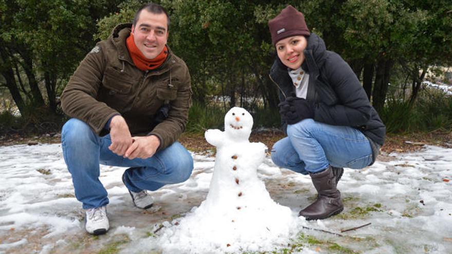 Una pareja posa junto a su muñeco de nieve, hoy, en la Serra