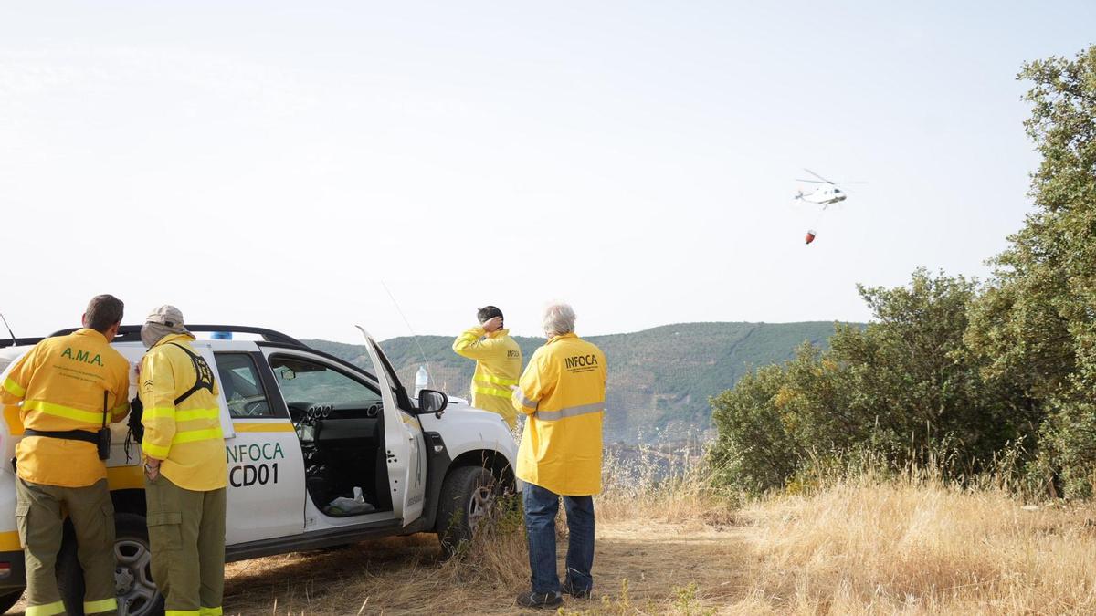 Personal del Infoca observa la evolución del incendio y los trabajos de un helicóptero.