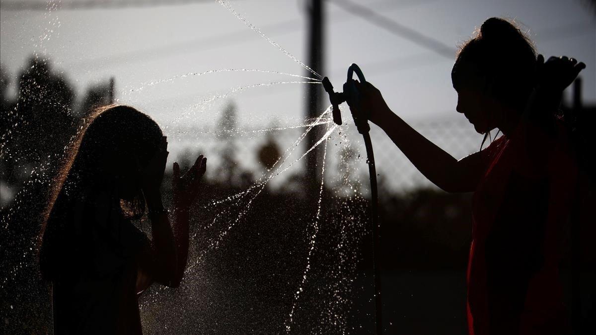 Unas niñas juegan con aspersores de agua en Córdoba, este domingo.