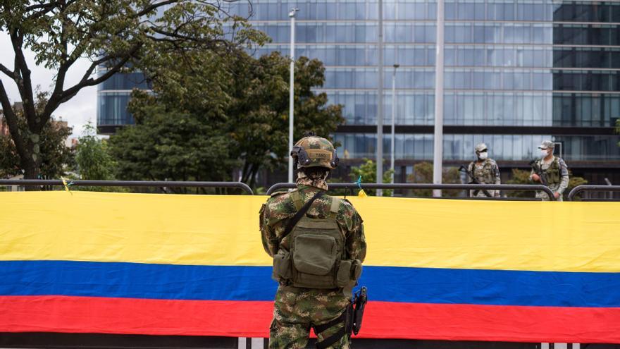 Un militar del Ejército de Colombia frente a la bandera nacional.