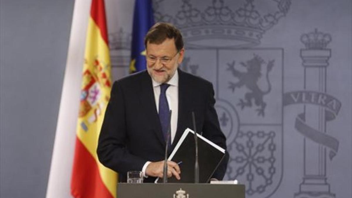 Rajoy recoge sus papeles tras la comparecencia en la Moncloa.