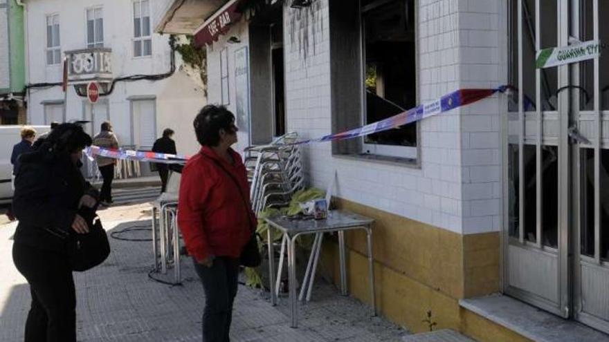 Una vecina contemplaba ayer el estado en el que permanece el Bar Galeón desde la explosión.  // N. Parga