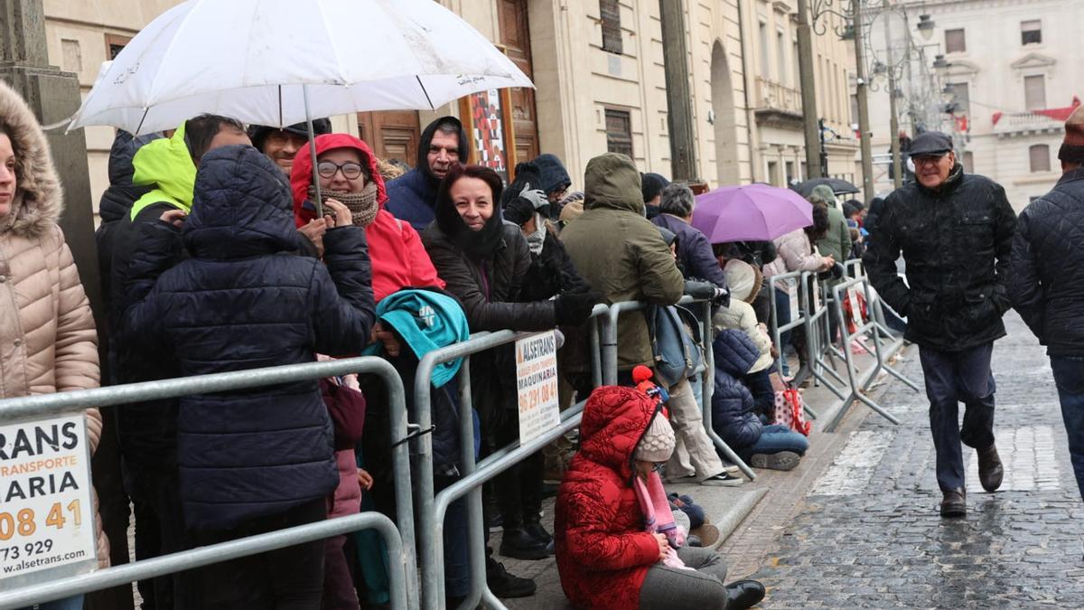 Más de 200 personas esperan en la plaza de España la llegada de los reyes con paraguas.