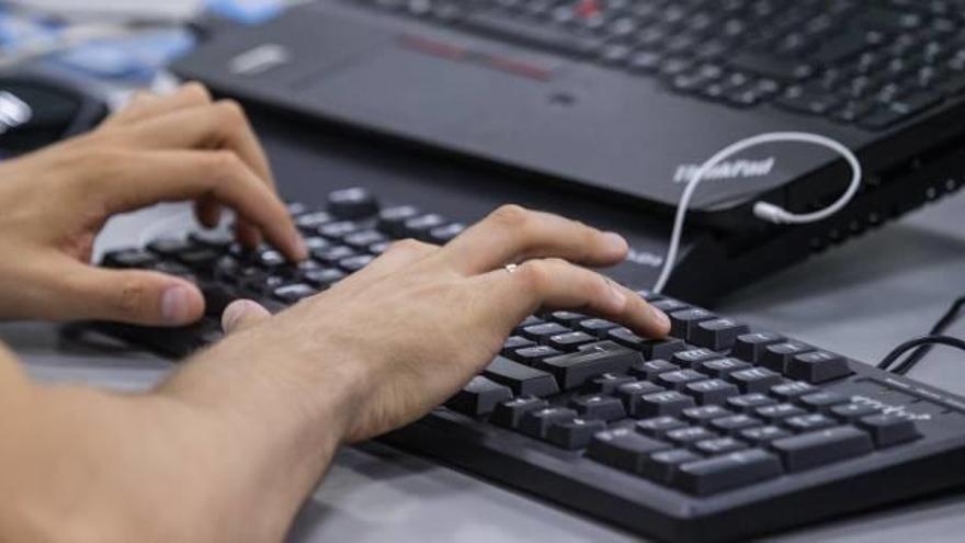 Imagen de una persona trabajando en una oficina con ordenadores.