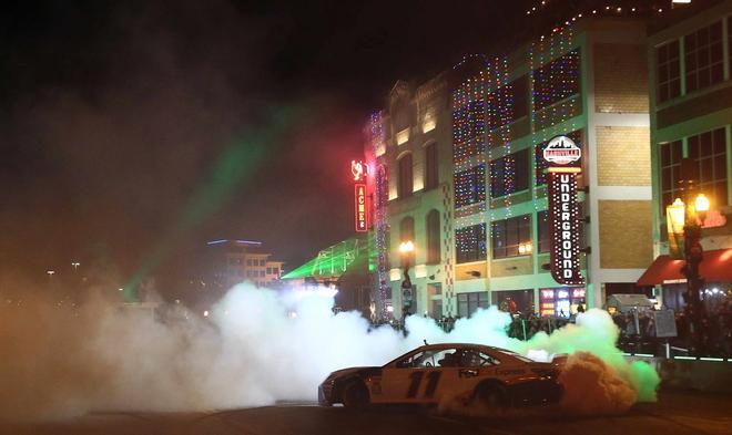 Denny Hamlin realiza un agotamiento durante los Burnouts de Monster Energy NASCAR Cup Series en Broadway en Nashville, Tennessee.