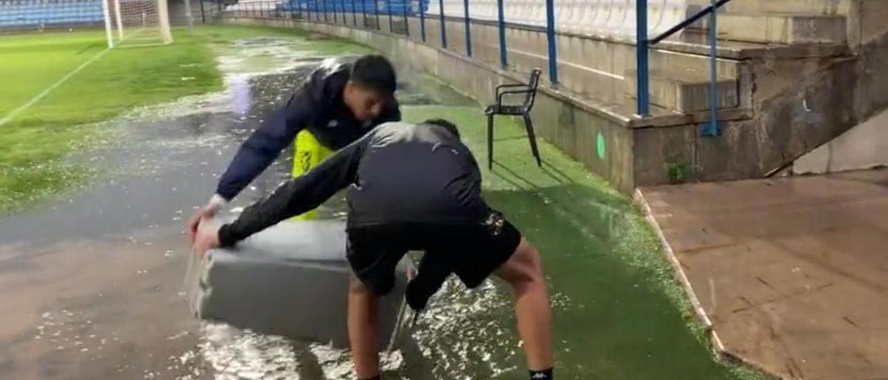Varios jugadores del Villanovense drenan el agua estancada en un córner.