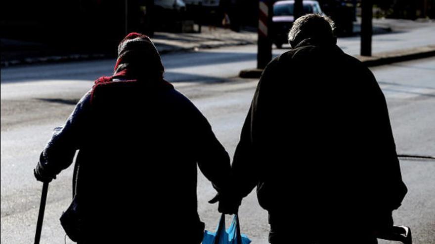 Dos ancianos pasean por la calle después de hacer la compra.