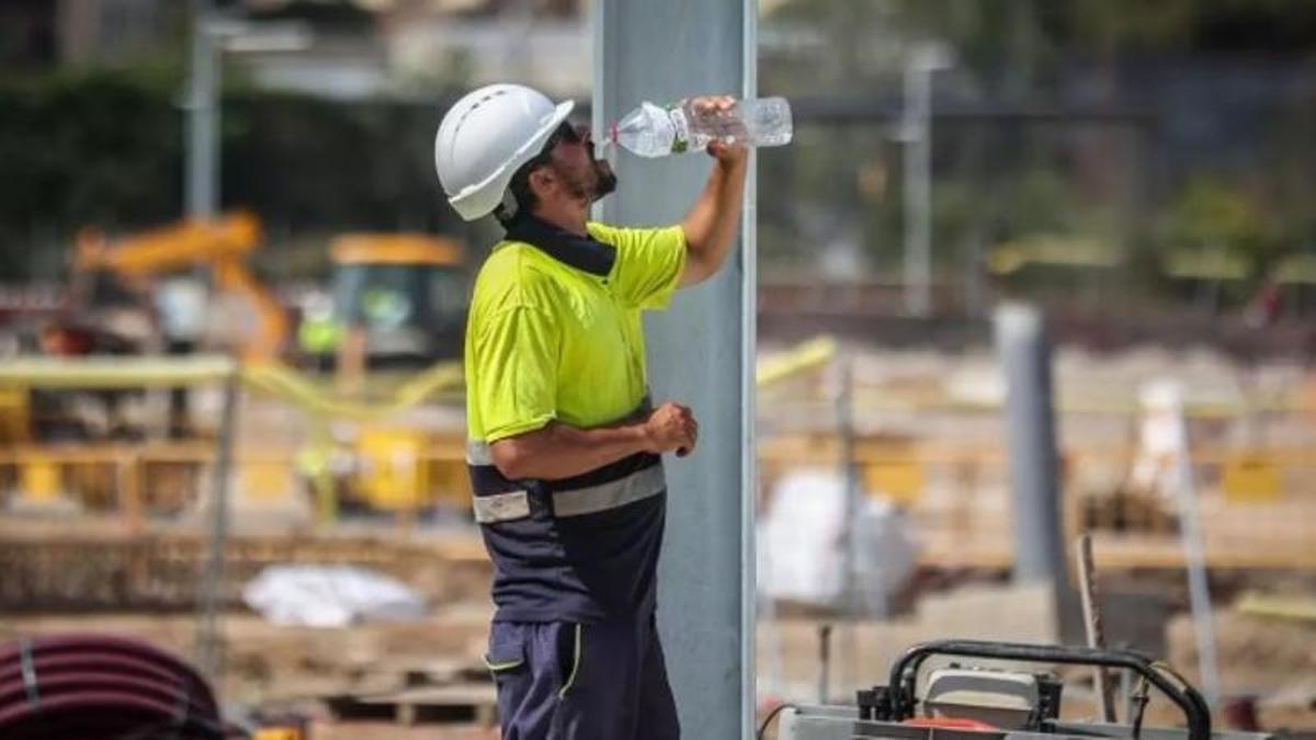 Un trabajador de la construcción bebe agua para hidratarse.
