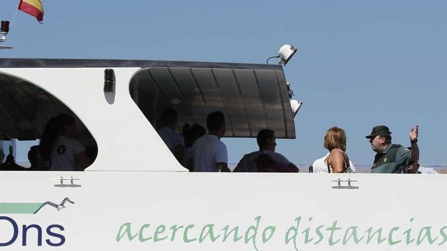 Un agente de la Guardia Civil indica a un grupo de turistas que abandone el barco atracado en Vigo. // J.L.