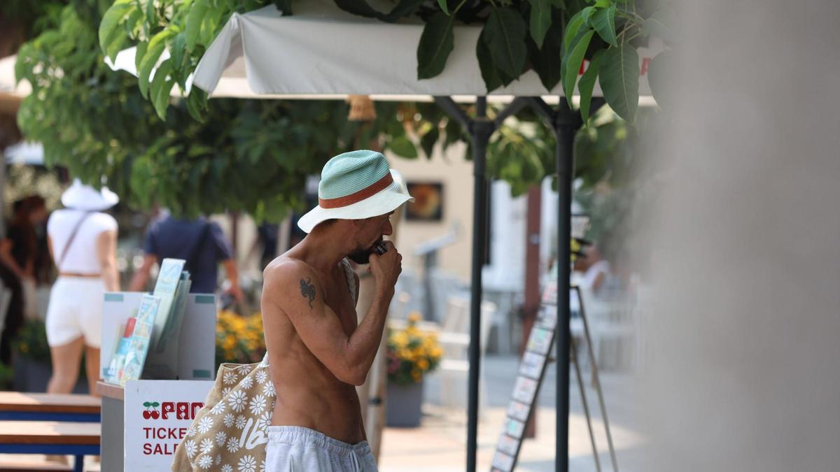 Un turista pasea sin camisa por Ibiza.