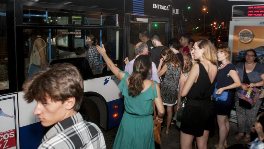 Jóvenes esperan un autobús durante las pasadas Hogueras