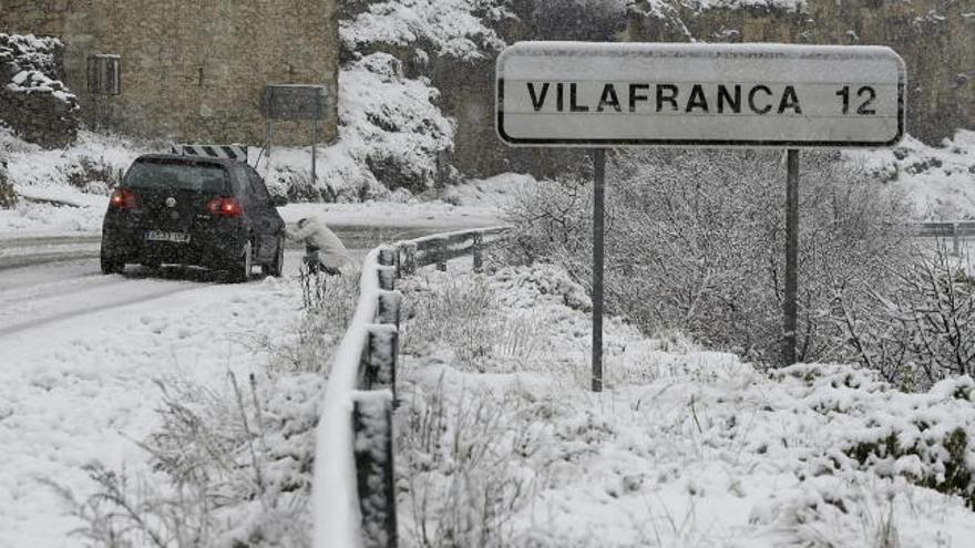 Una conductora coloca las cadenas en el Coll d&#039;Ares a unos 1100 m de altitud, tras la primera nevada importante en las comarcas del norte de Castellón que ha acumulado entre 5 y 15 cm de nieve.