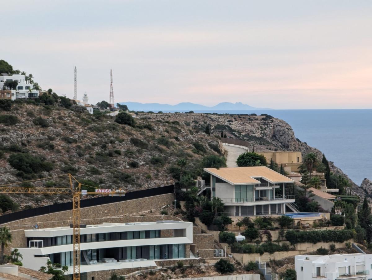 Chalés de la Corona, el faro y la silueta de la isla de Ibiza