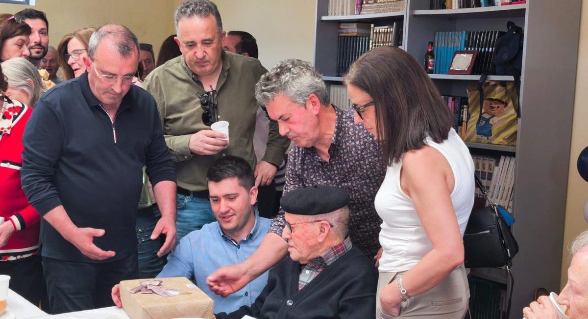 Timoteo Ballesteros, rodeado de sus hijos (de pie) y con el alcalde de la localidad, se dispone a abrir el obsequio del Ayuntamiento. | CEDIDA