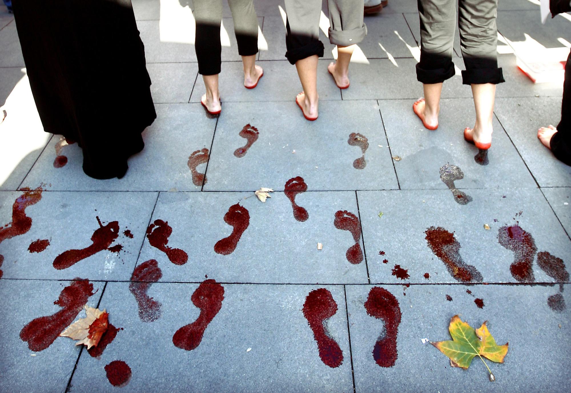 Unas mujeres dejan las huellas de sus pies teñidos de rojo durante la manifestación celebrada en Sevilla y convocada por la Plataforma 8 de Marzo con motivo del Día Internacional contra la Violencia hacia las Mujeres.