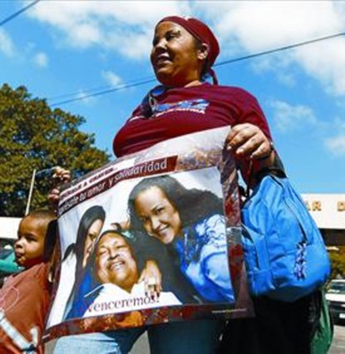Una dona mostra una foto de Chávez amb les seves dues filles.
