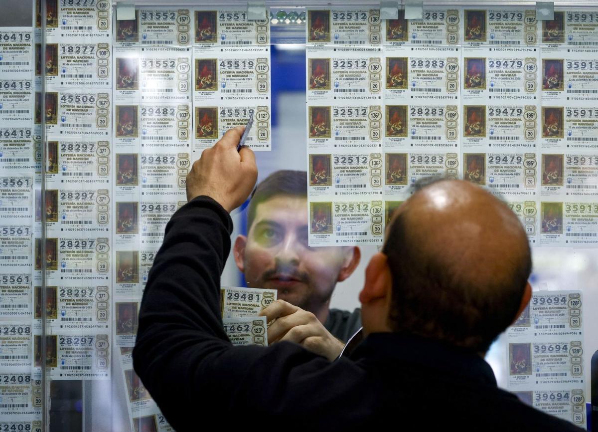 Un hombre elige un décimo de Navidad en una administración de lotería.
